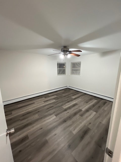 spare room featuring dark wood finished floors, a baseboard heating unit, and ceiling fan