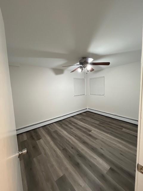 spare room with dark wood-type flooring, baseboard heating, and a ceiling fan