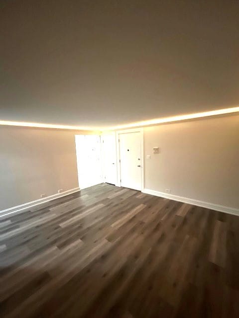 unfurnished room featuring baseboards and dark wood-style flooring