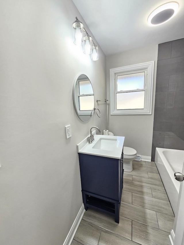 full bathroom with toilet, vanity, baseboards, and a tub to relax in