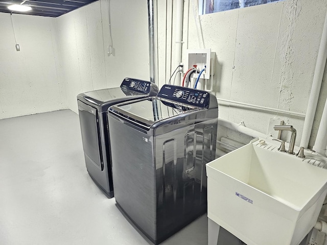 washroom featuring washer and clothes dryer, laundry area, and a sink