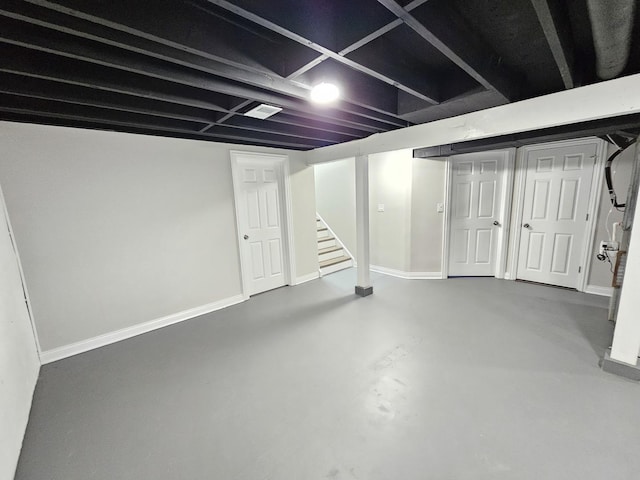 finished below grade area featuring stairway, visible vents, and baseboards