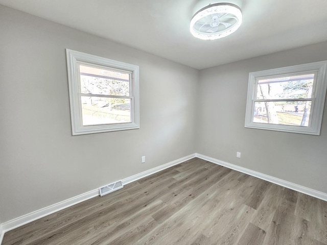 unfurnished room featuring visible vents, baseboards, and wood finished floors