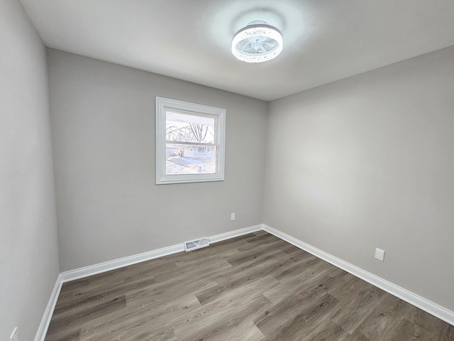 unfurnished room featuring visible vents, baseboards, and dark wood-style floors