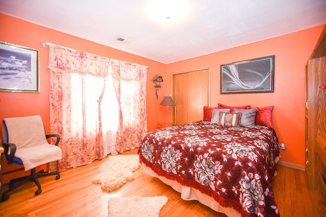 bedroom with wood finished floors, visible vents, and baseboards