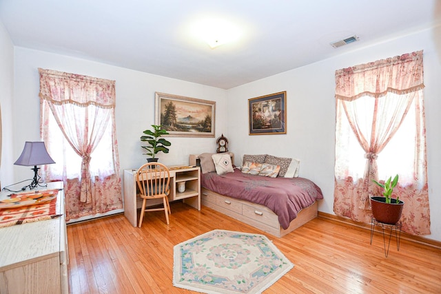 bedroom featuring visible vents, multiple windows, baseboards, and wood-type flooring