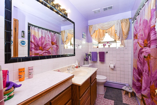 bathroom with visible vents, tile walls, toilet, baseboard heating, and vanity