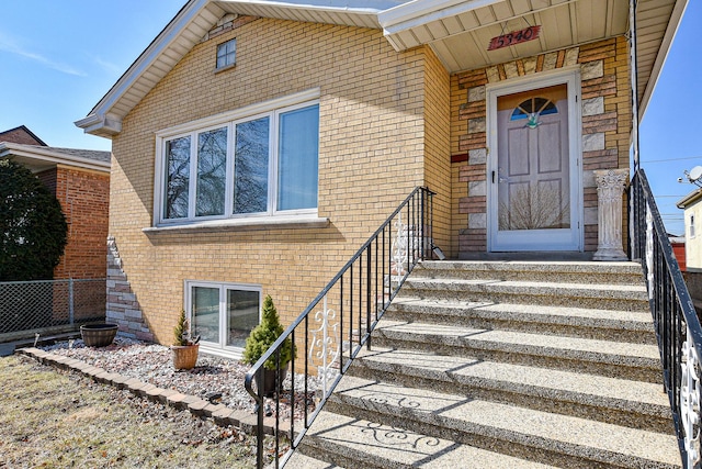 doorway to property with brick siding and fence