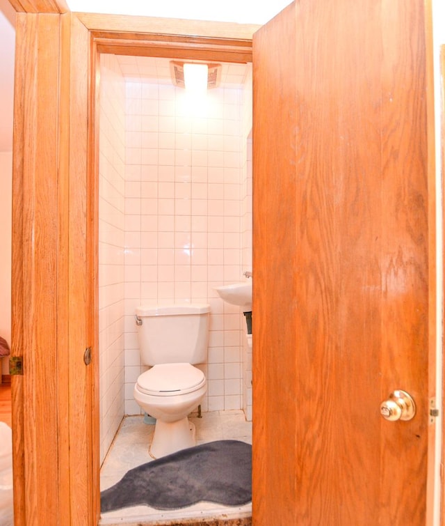 bathroom with tile walls, toilet, and tile patterned floors