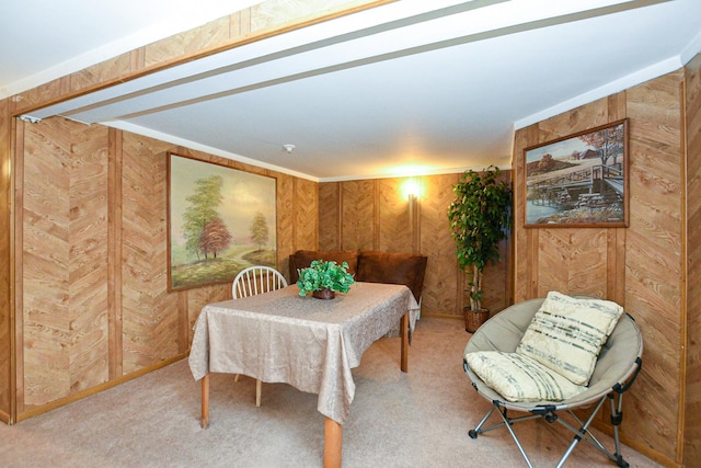 carpeted dining room with wood walls and ornamental molding