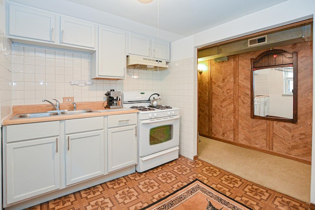 kitchen featuring visible vents, under cabinet range hood, light floors, white gas range oven, and a sink