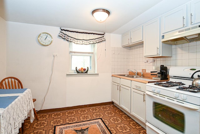 kitchen featuring tasteful backsplash, baseboards, under cabinet range hood, white gas range oven, and a sink