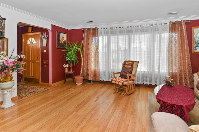 living area with arched walkways, visible vents, crown molding, and wood finished floors