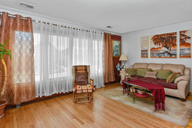 living area with visible vents, ornamental molding, and hardwood / wood-style flooring