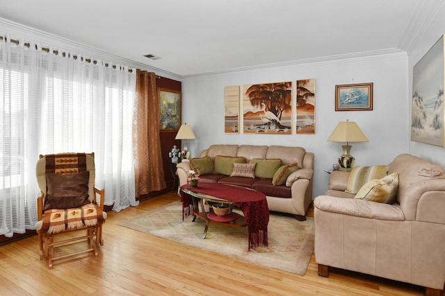 living area with visible vents, wood finished floors, and ornamental molding