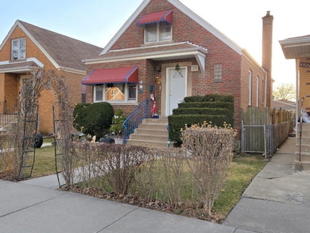 tudor-style house featuring brick siding, a gate, and fence