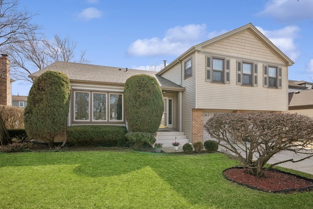 split level home featuring brick siding, concrete driveway, a front yard, and roof with shingles