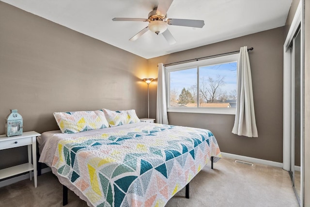 carpeted bedroom with visible vents, baseboards, and a ceiling fan