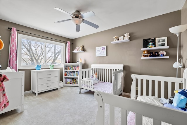 bedroom featuring baseboards, a crib, carpet, and ceiling fan