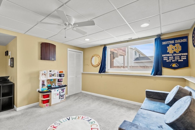 interior space featuring carpet flooring, a ceiling fan, baseboards, and a drop ceiling