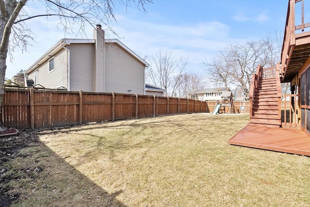 view of yard with a wooden deck, fence, stairs, and a playground