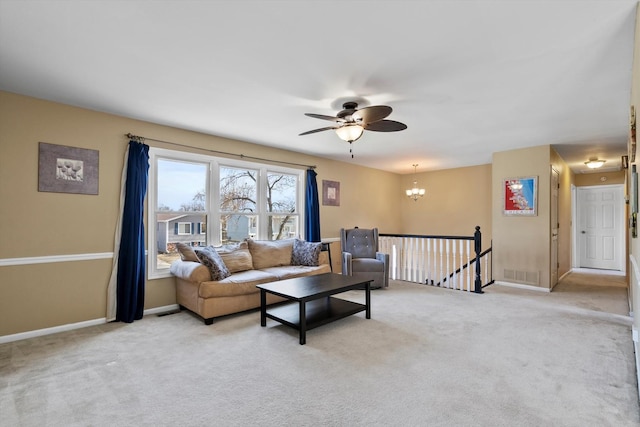 carpeted living room with baseboards and ceiling fan with notable chandelier