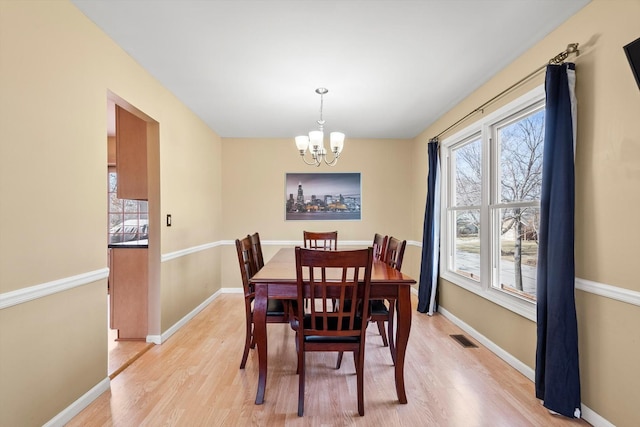 dining room featuring visible vents, baseboards, and light wood finished floors