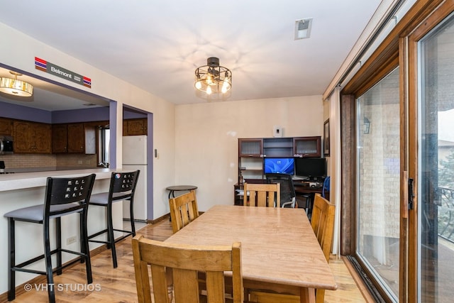 dining space with light wood finished floors, visible vents, and an inviting chandelier