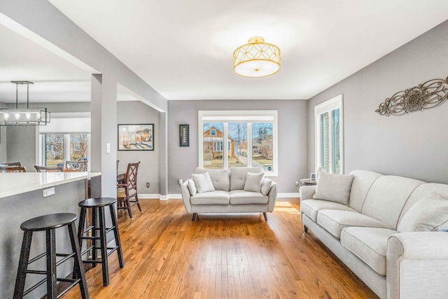 living area featuring a notable chandelier, baseboards, and light wood-style floors