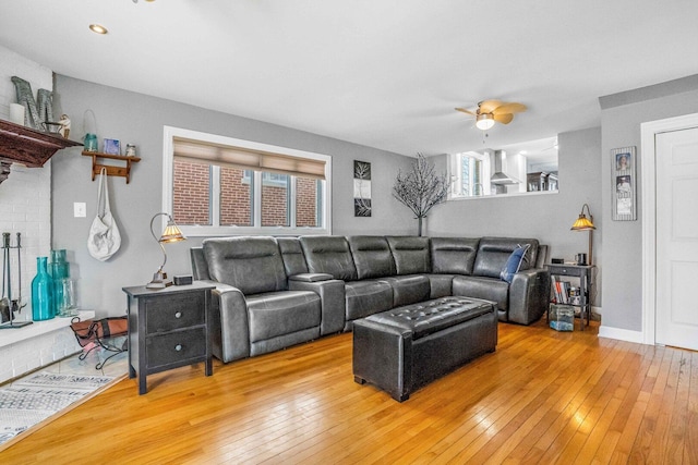 living area with baseboards, light wood-style floors, and a ceiling fan