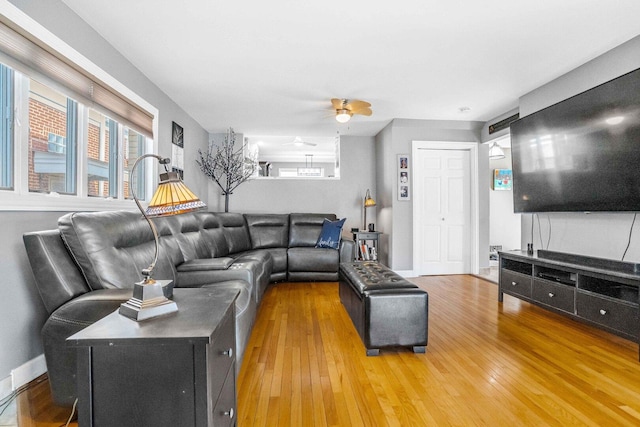 living room with ceiling fan, baseboards, and wood-type flooring