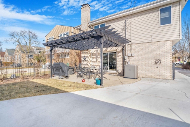 rear view of property featuring brick siding, fence, a chimney, a pergola, and a patio