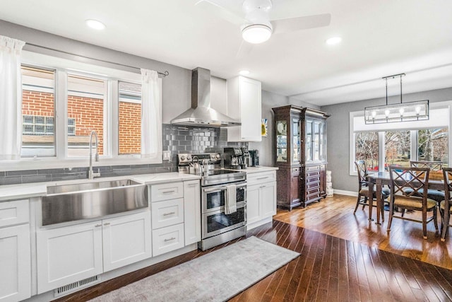 kitchen with visible vents, a sink, double oven range, wall chimney exhaust hood, and decorative backsplash