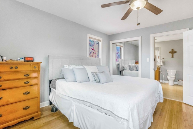 bedroom with a closet, ensuite bath, light wood-type flooring, and baseboards