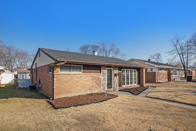 back of property with a yard, central air condition unit, brick siding, and fence