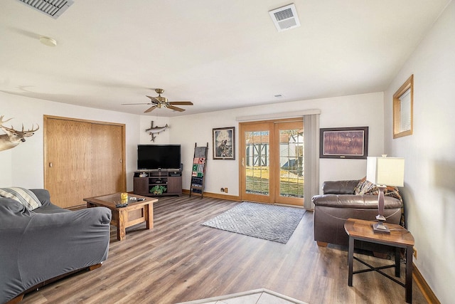 living area with ceiling fan, visible vents, baseboards, and wood finished floors