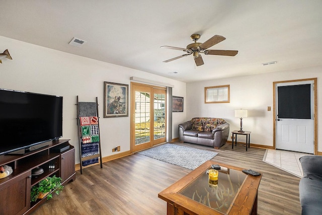 living area featuring baseboards, wood finished floors, visible vents, and ceiling fan