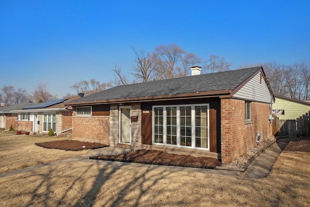 back of property with fence, brick siding, and a chimney