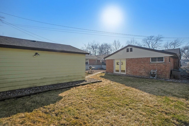 exterior space with brick siding, a lawn, and fence