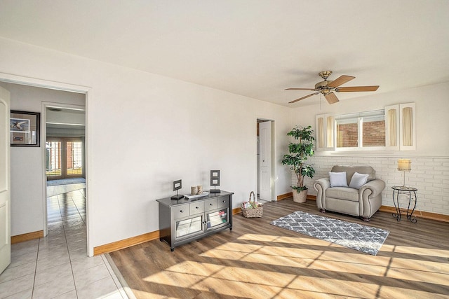 living room featuring ceiling fan, baseboards, and light wood-style flooring