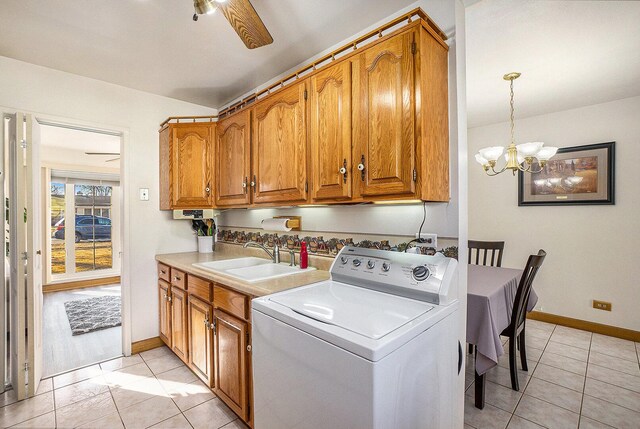 laundry room with light tile patterned floors, ceiling fan with notable chandelier, cabinet space, washer / clothes dryer, and a sink