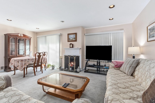 carpeted living area with a fireplace with flush hearth and recessed lighting