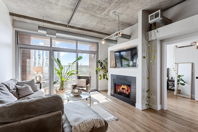 living area featuring visible vents, baseboards, wood finished floors, and a tiled fireplace