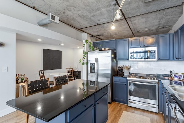 kitchen featuring dark countertops, blue cabinetry, and appliances with stainless steel finishes