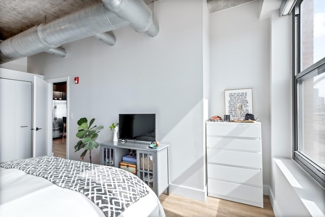 bedroom featuring baseboards, stainless steel fridge, and wood finished floors