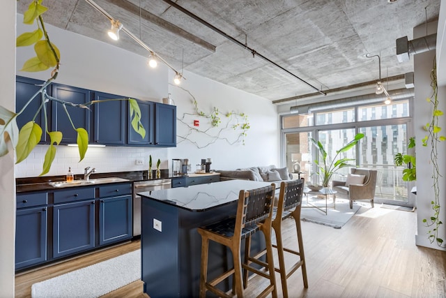 kitchen with wood finished floors, blue cabinetry, a sink, dishwasher, and open floor plan