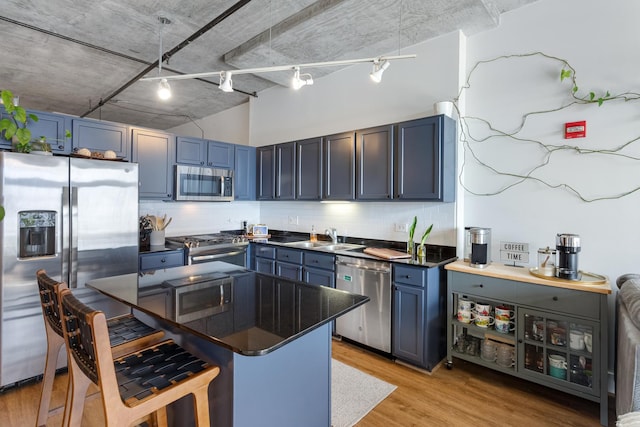 kitchen with blue cabinets, light wood-type flooring, a sink, appliances with stainless steel finishes, and a breakfast bar area