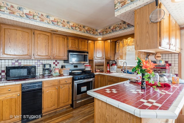 kitchen featuring a sink, stainless steel appliances, tile countertops, and dark wood-style flooring