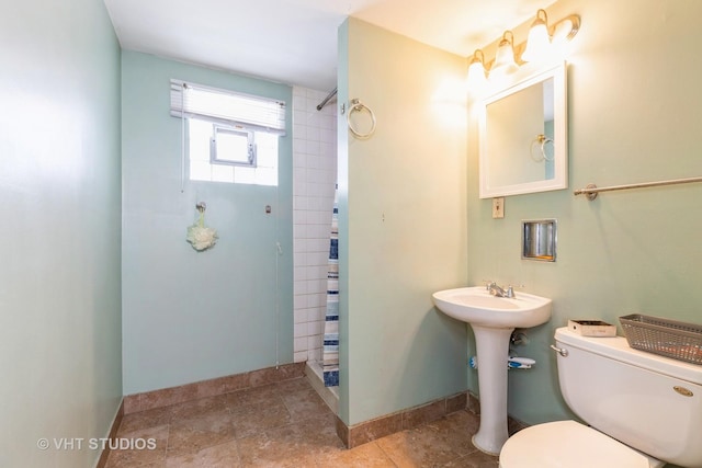 full bath featuring curtained shower, toilet, and baseboards