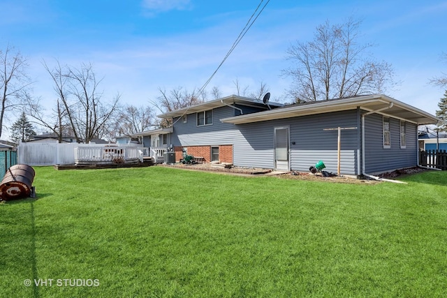 back of property featuring a lawn, a wooden deck, and fence